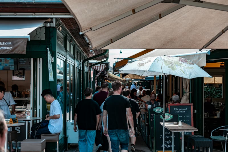 Mensen lopen langs terrassen en kraampjes in een marktstraat