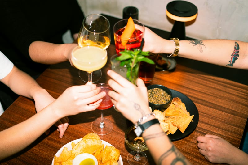 Proostende handen boven een tafel met drankjes en hapjes