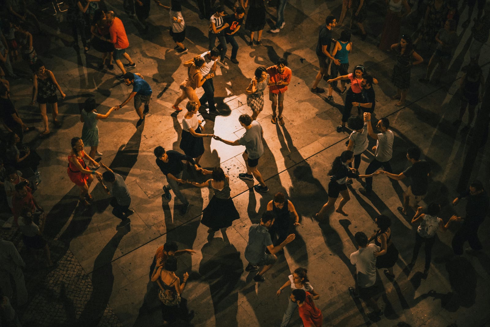Dansers op een plein in warm licht, van boven gezien